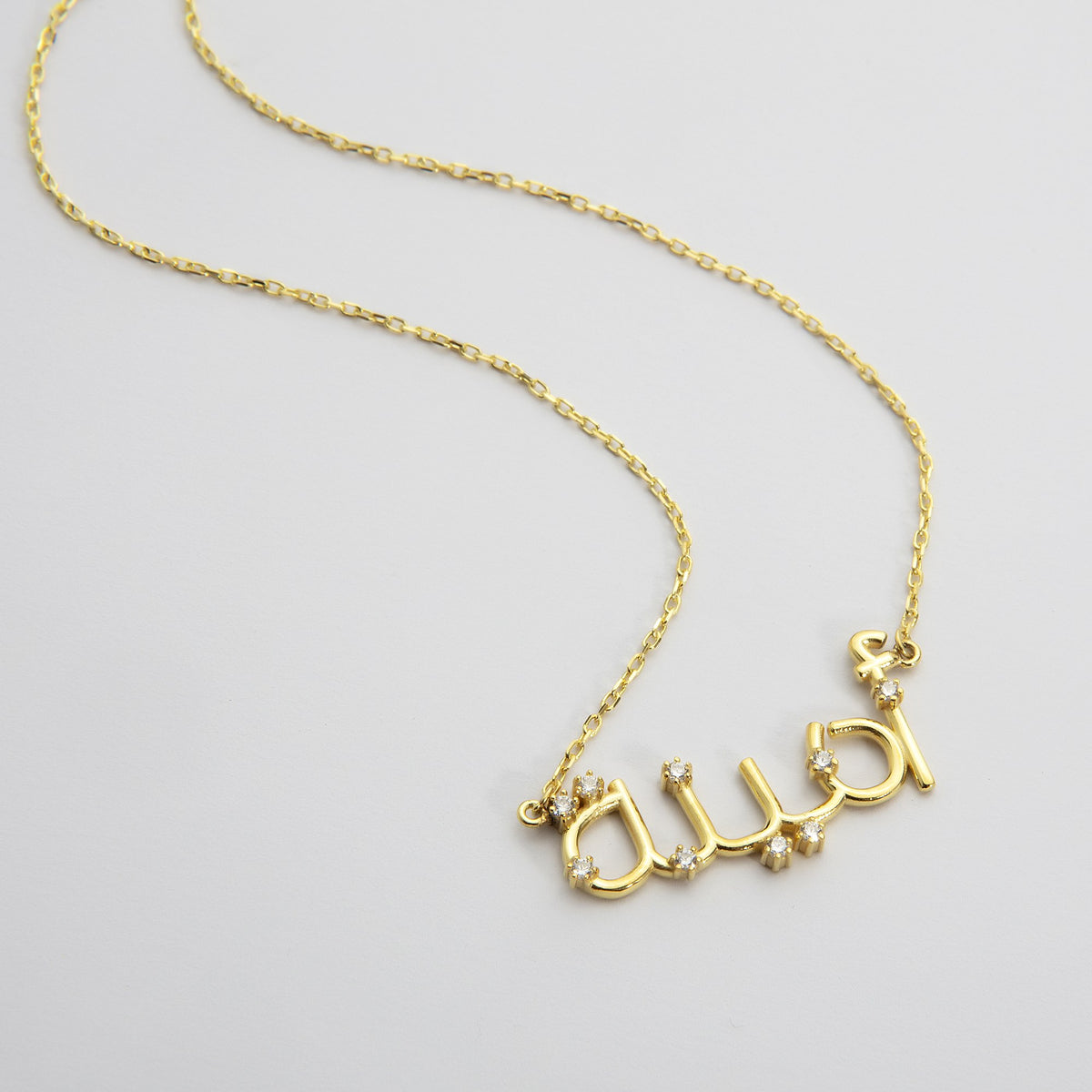 Gold Arabic nameplate necklace spelling a name in Arabic script on a cable chain