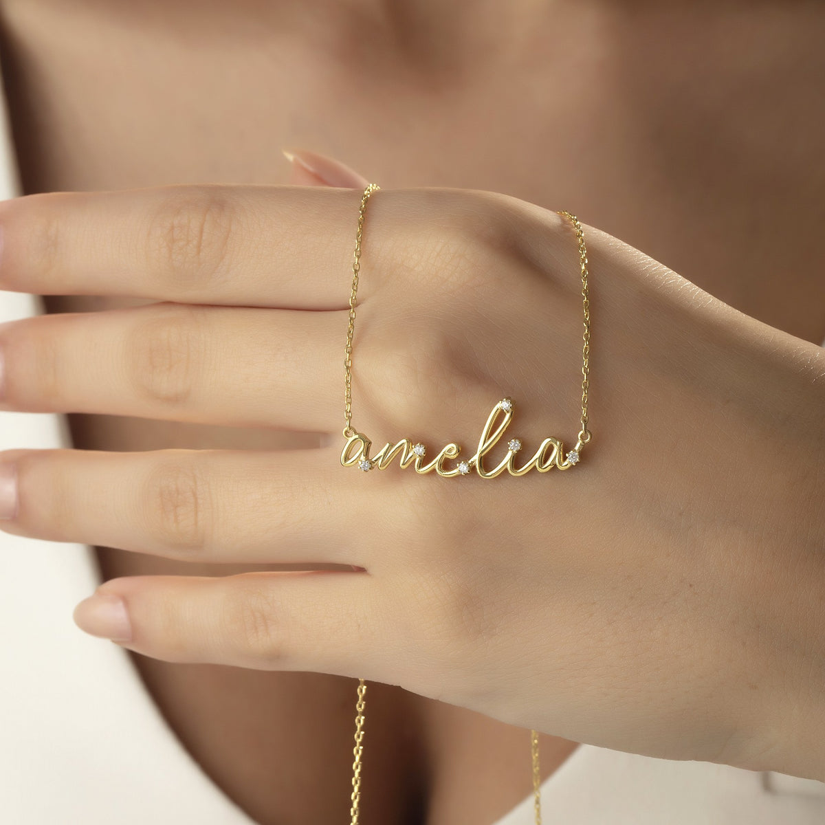 Cursive name necklace for mom with child's name draped over a hand