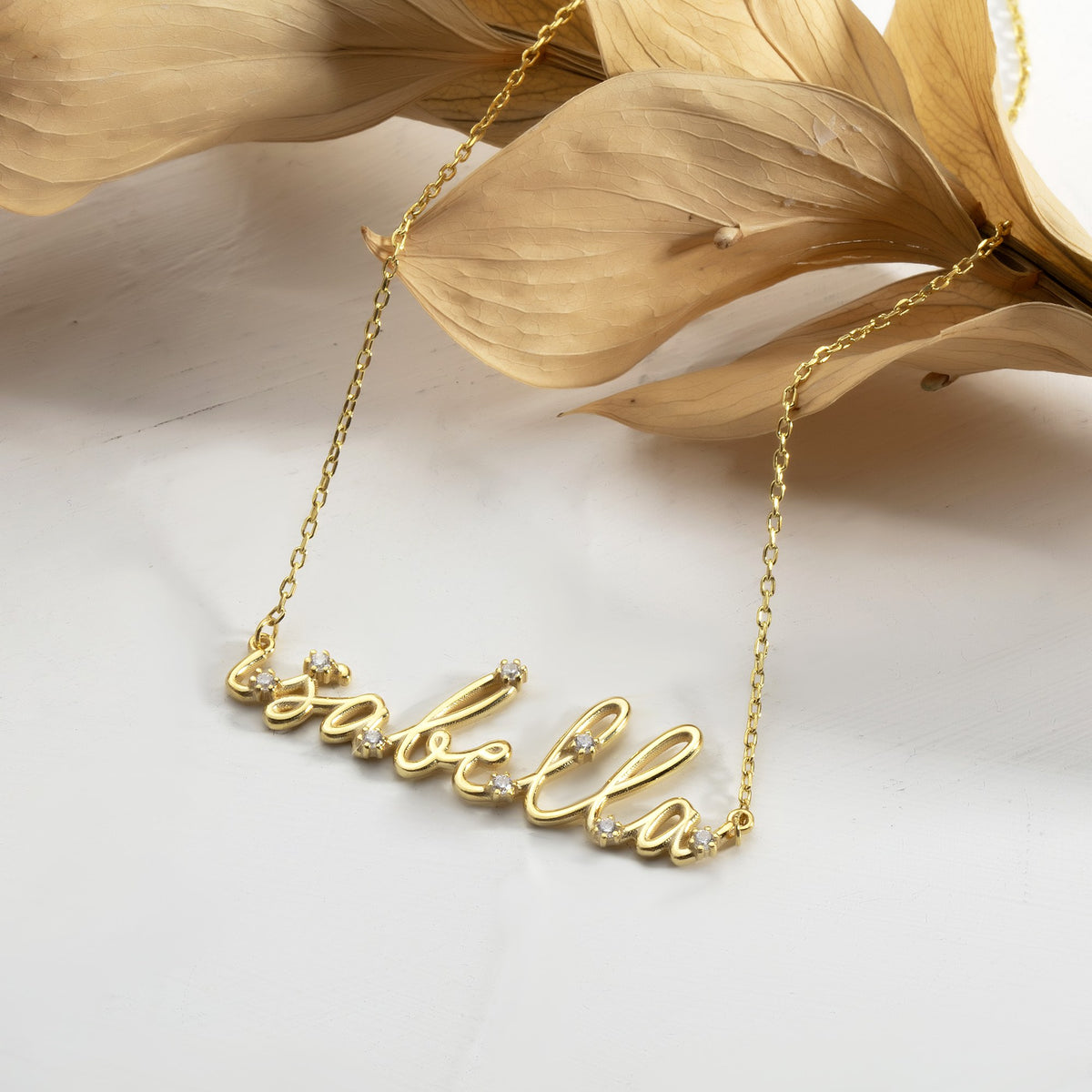 Dainty gold name necklace with tiny CZ accents on a fine cable chain