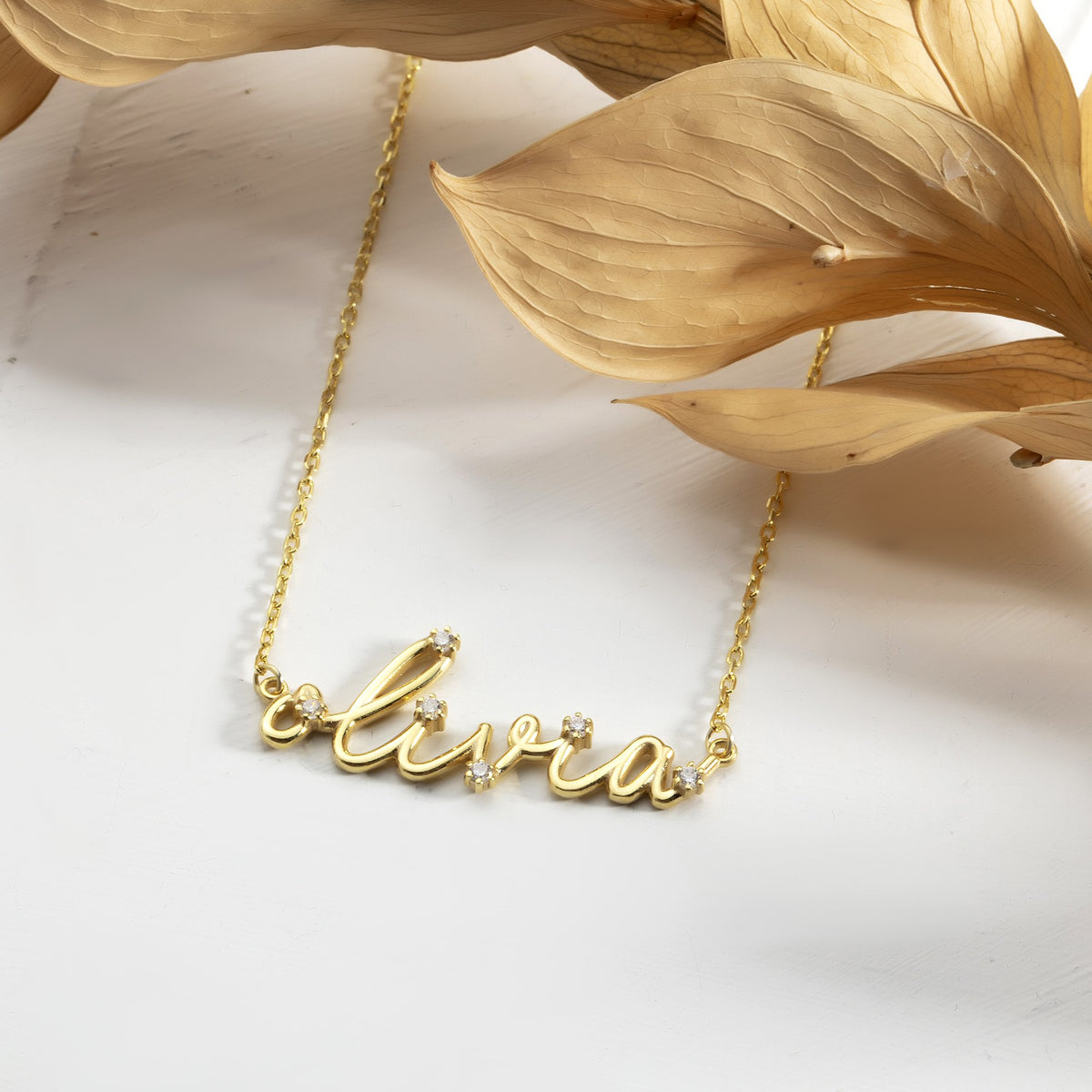 Close-up of prong-set simulated diamond stones on a gold script nameplate