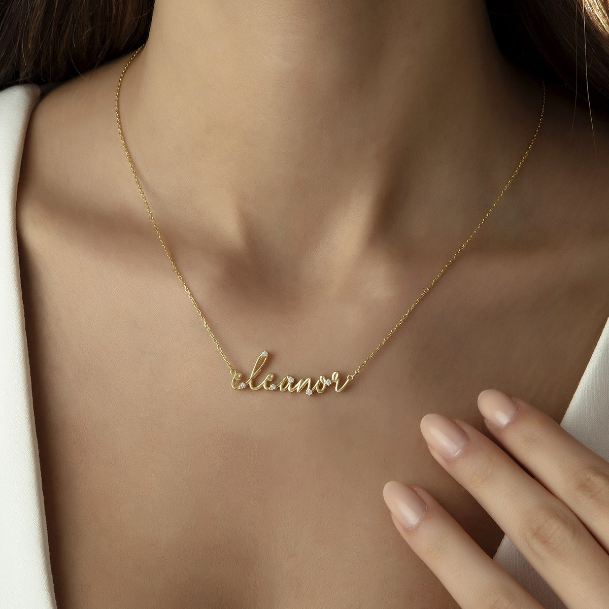Gold script name necklace with diamond-look CZ stones worn by a woman