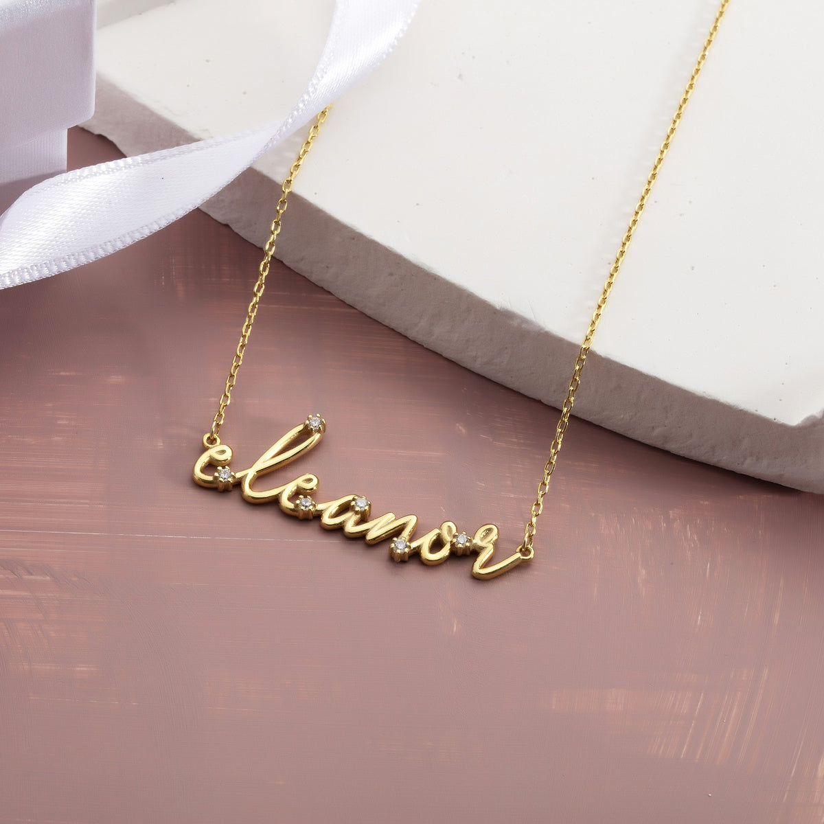 Custom cursive nameplate necklace close-up showing prong-set CZ stones