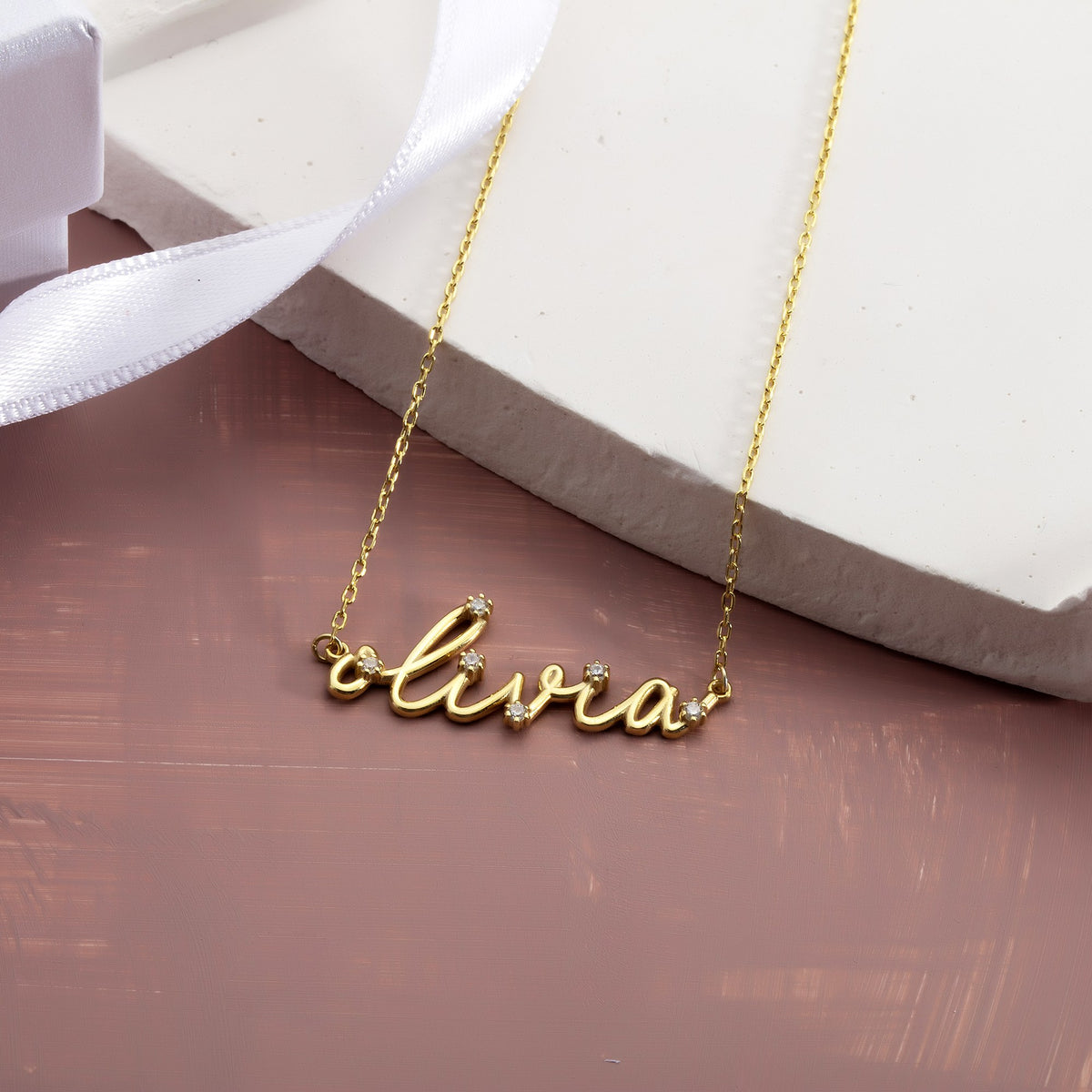 Diamond-look name necklace with simulated diamonds beside a white gift box and ribbon