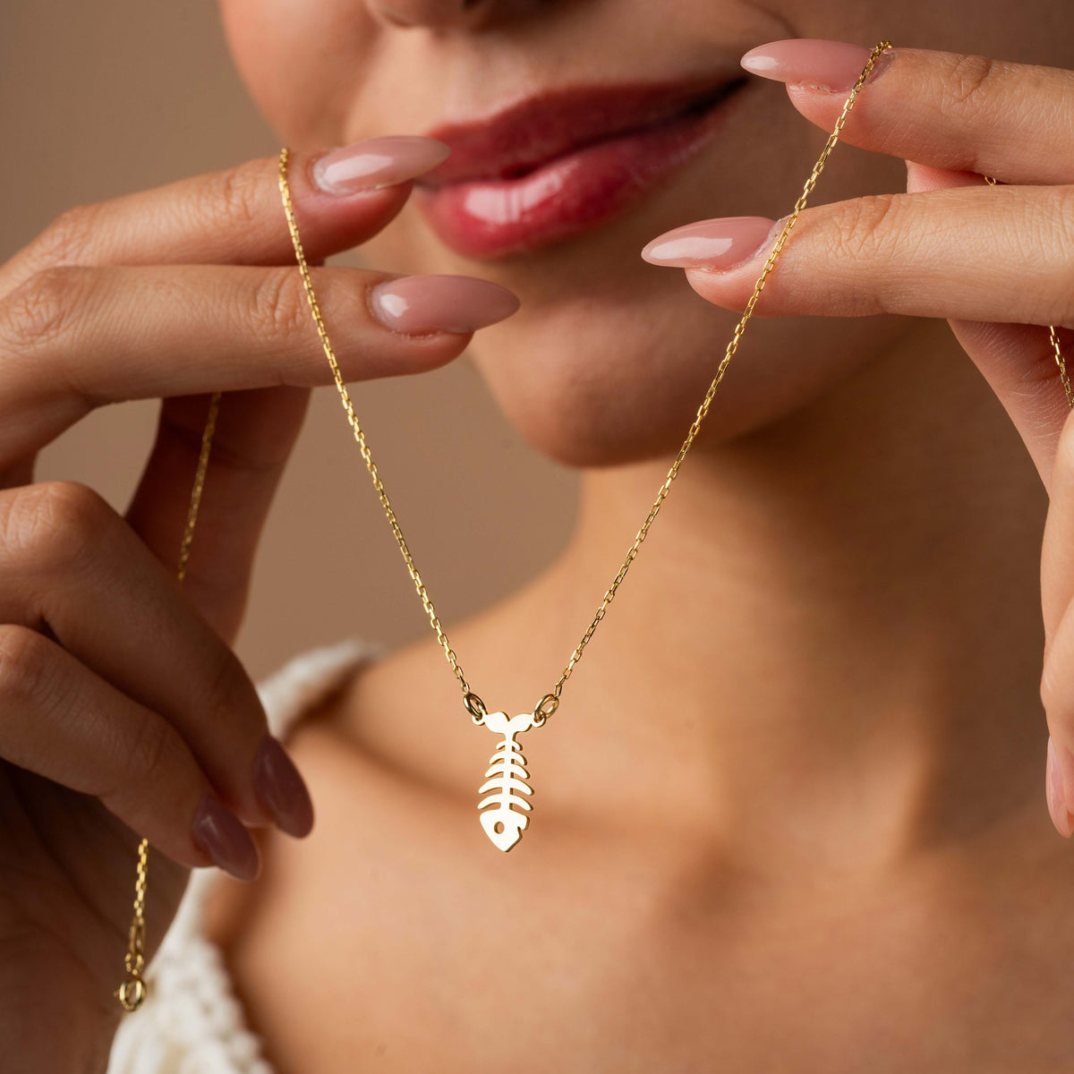Gold fish bone necklace held up on a dainty cable chain