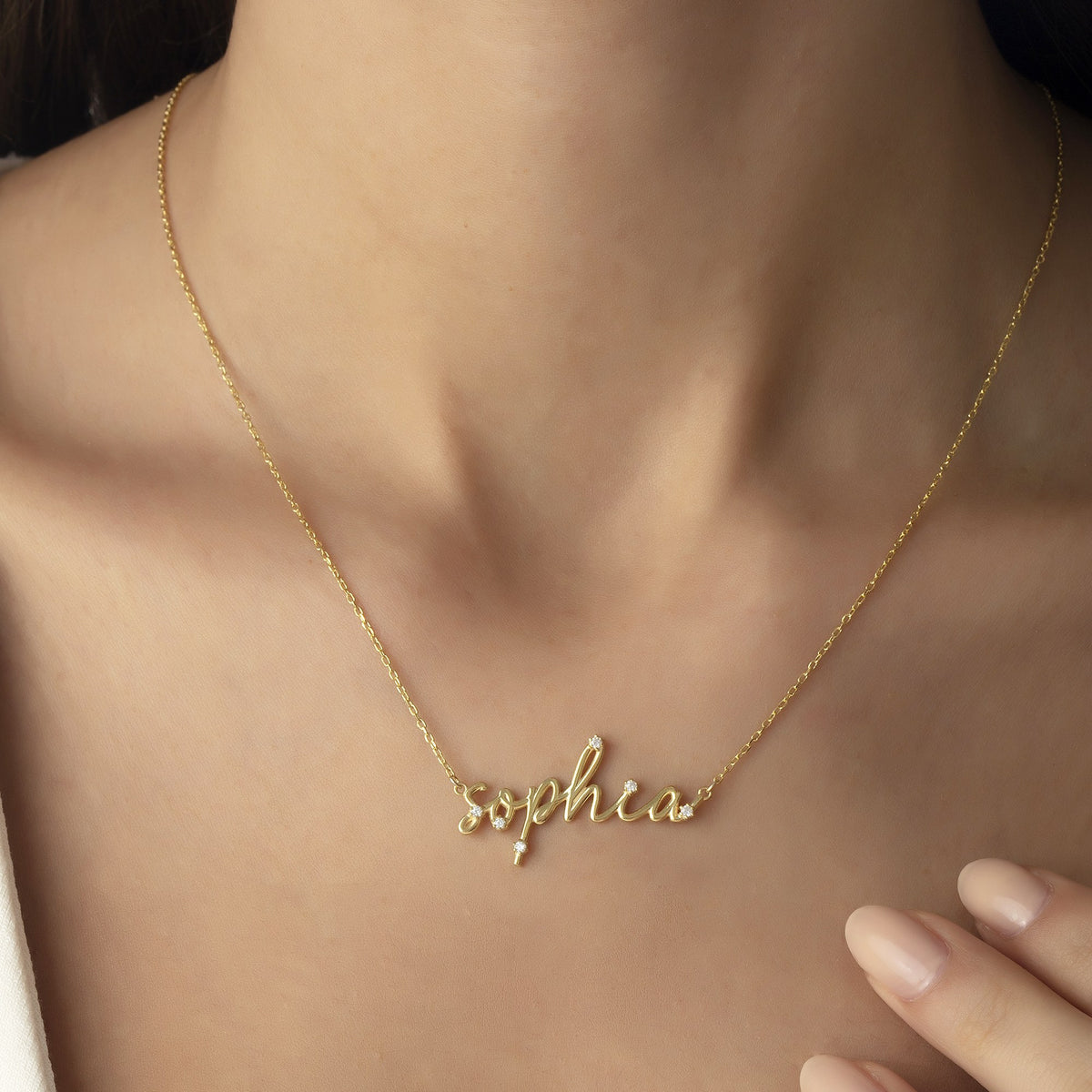 Woman wearing a personalized gold name necklace with CZ stones