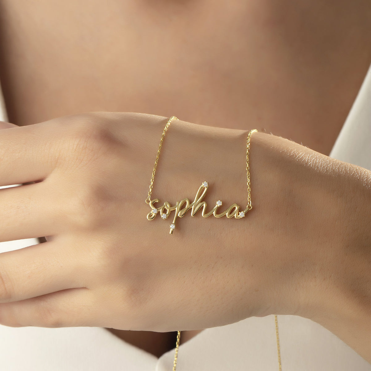 Custom script name necklace for women draped over a hand